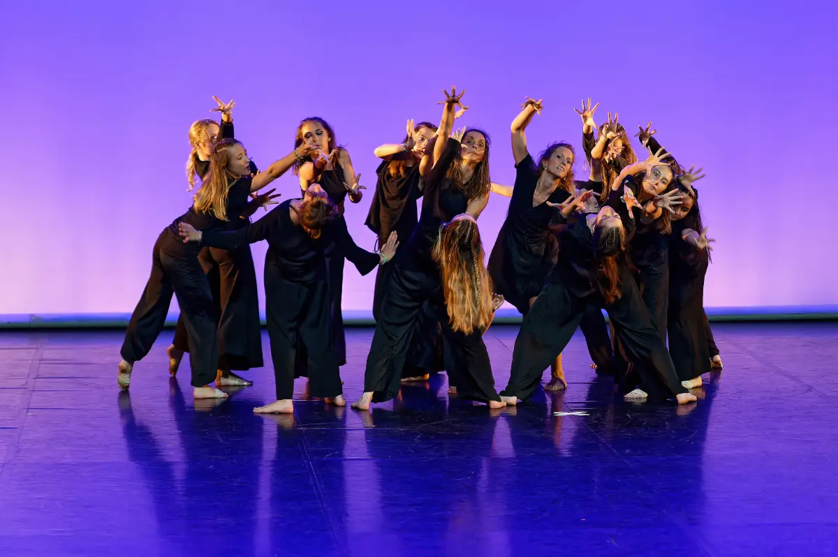 2023-06-17-_DSC_4257-NEFKa-Danse-denoise-faceai Danseuses en chemises blanches et jeans sur scène lors du gala de Ka'Danse à Arcachon, lumière bleue de spectacle, bras levés